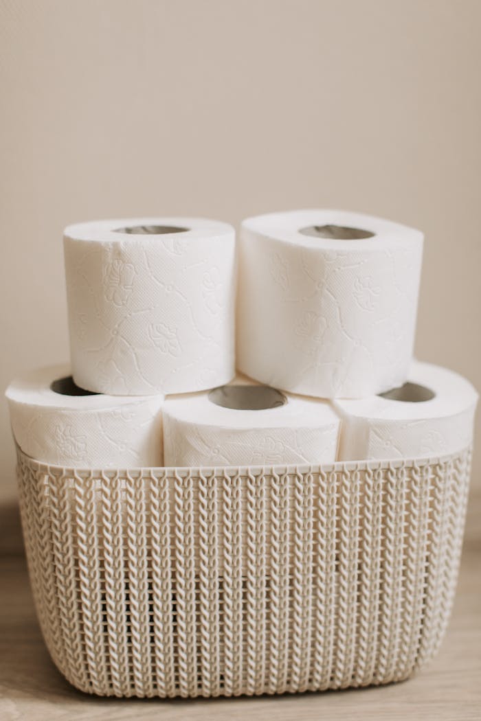 A neat stack of white toilet paper rolls in a wicker basket indoors.
